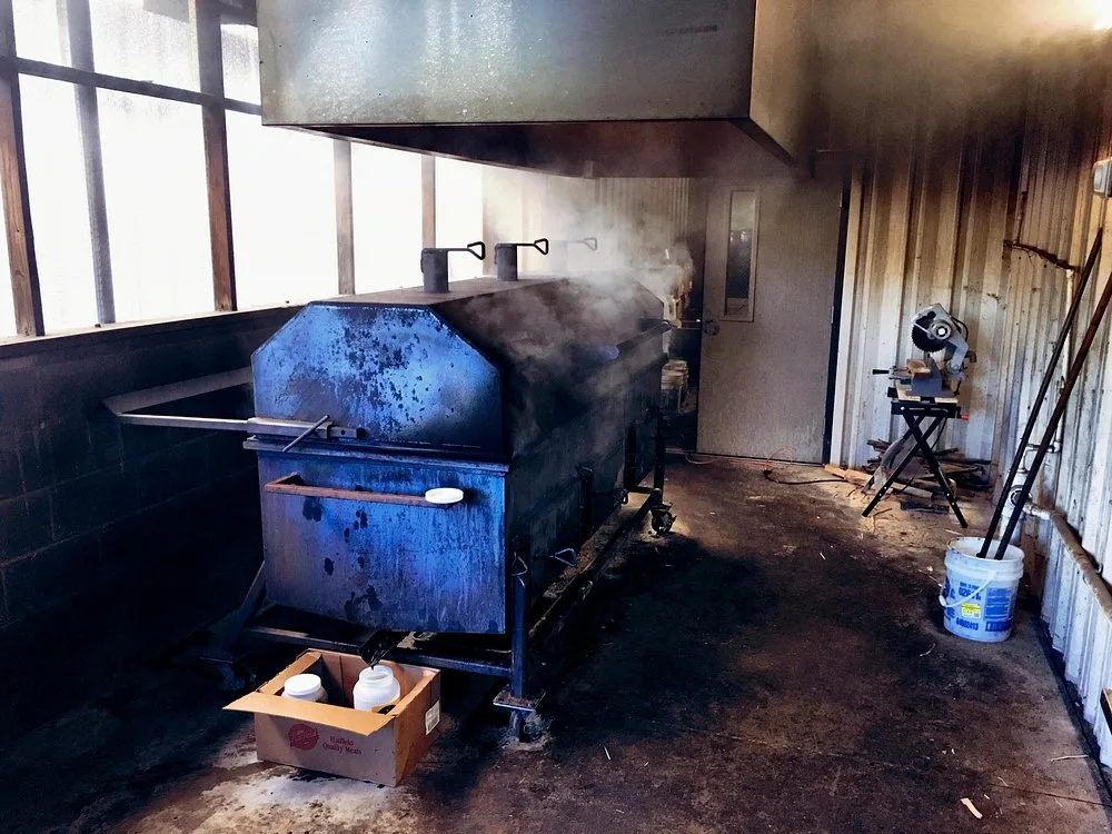 The steel pit smoker inside BBQ King's smokehouse, steam rising from the firebox