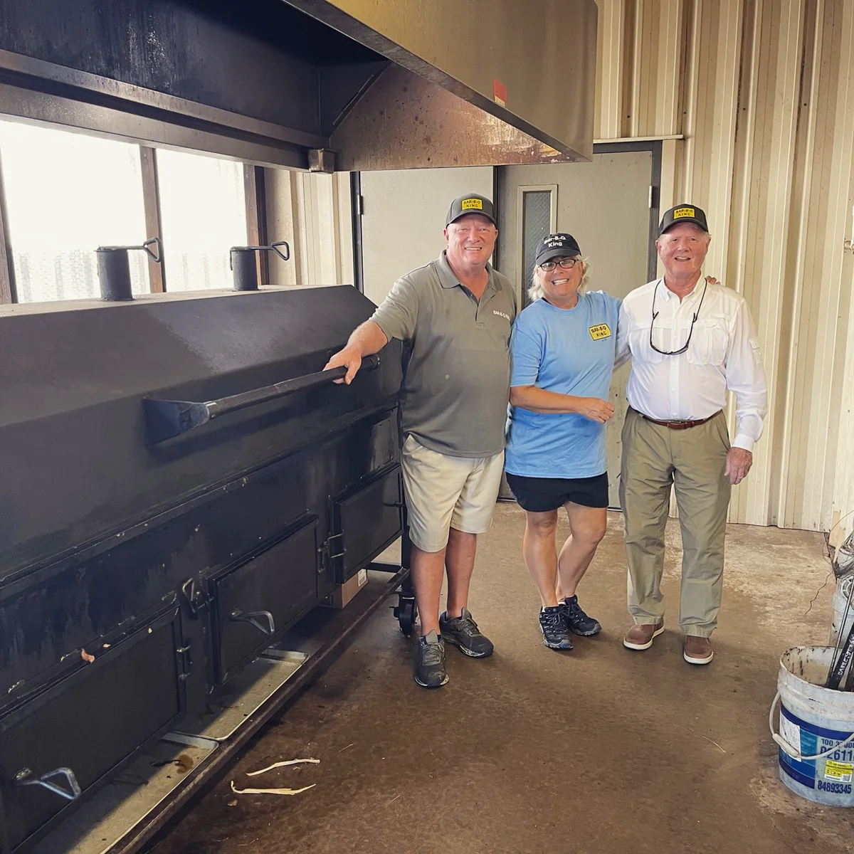 Staff and guests portrait in front of the pit smoker